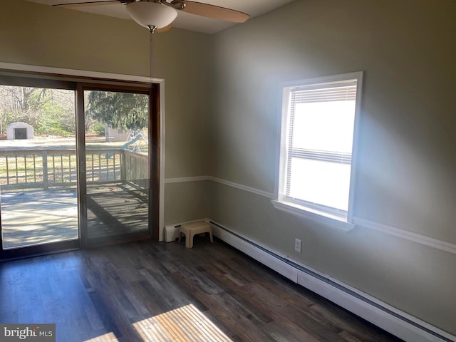 spare room featuring dark wood finished floors, a baseboard heating unit, and a ceiling fan