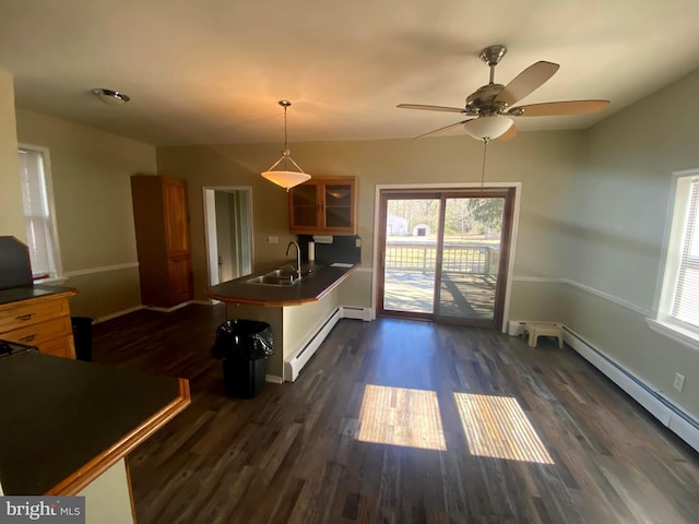 kitchen with a sink, glass insert cabinets, a peninsula, a baseboard radiator, and dark wood-style flooring