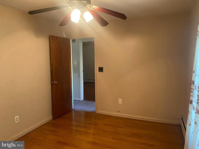 spare room with wood finished floors, baseboards, baseboard heating, and ceiling fan