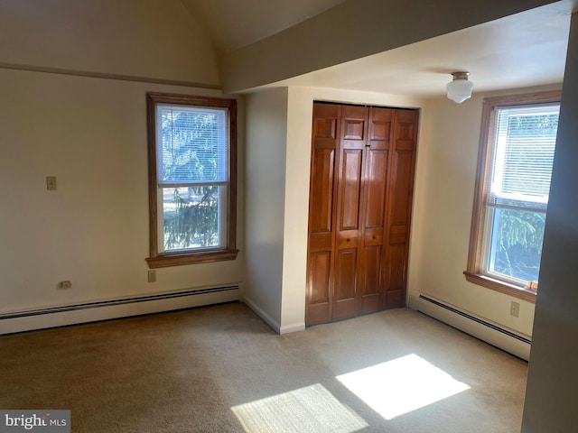 unfurnished bedroom with lofted ceiling, a closet, baseboard heating, and light carpet