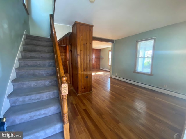 stairs with baseboards, baseboard heating, and wood finished floors