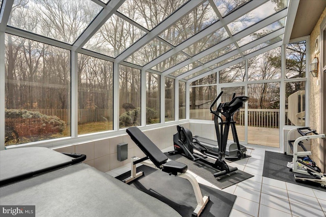 exercise area with plenty of natural light, a high ceiling, tile patterned flooring, and a sunroom