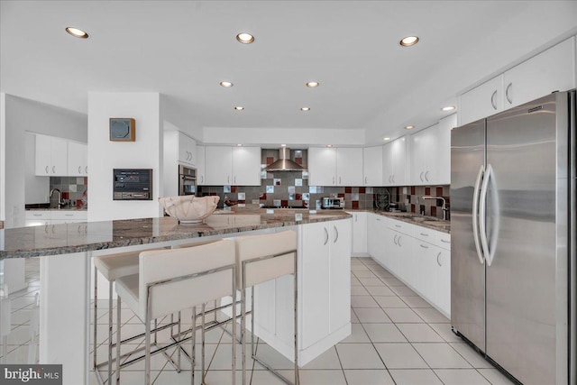 kitchen with tasteful backsplash, wall chimney range hood, light tile patterned floors, stainless steel appliances, and a sink