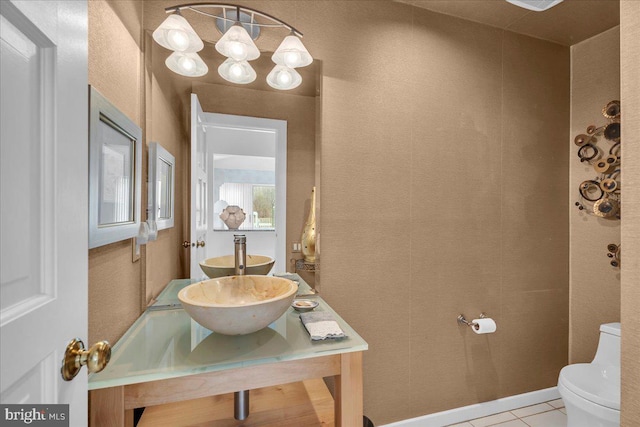 half bathroom featuring tile patterned floors, toilet, and a sink