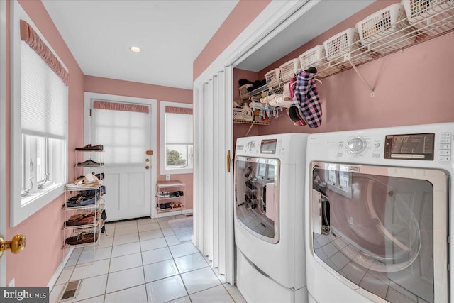 clothes washing area with light tile patterned floors, visible vents, washer and dryer, and laundry area