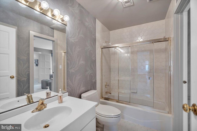 full bathroom with visible vents, toilet, shower / bath combination with glass door, wallpapered walls, and vanity