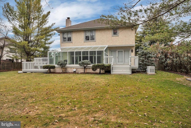 rear view of house featuring stucco siding, a chimney, a yard, and a sunroom