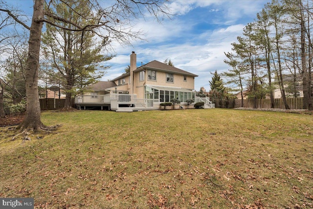 rear view of house featuring a yard, a fenced backyard, a sunroom, a chimney, and a deck