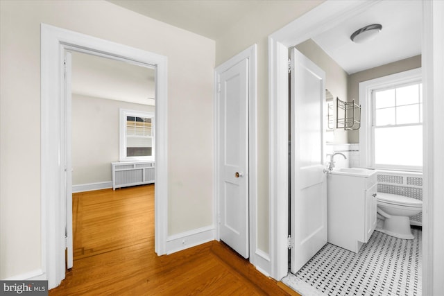 bathroom featuring toilet, wood finished floors, radiator, baseboards, and vanity