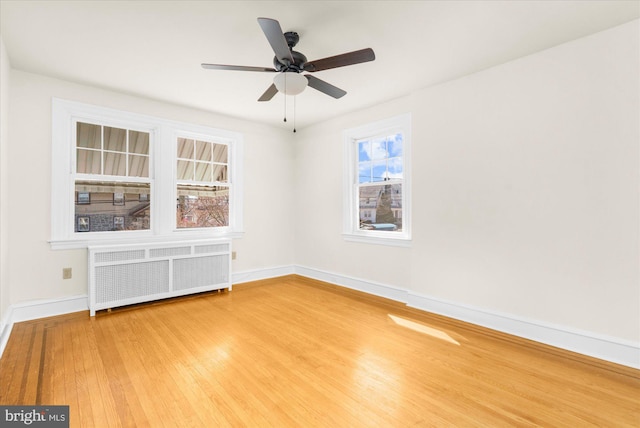 spare room with ceiling fan, radiator heating unit, baseboards, and wood finished floors