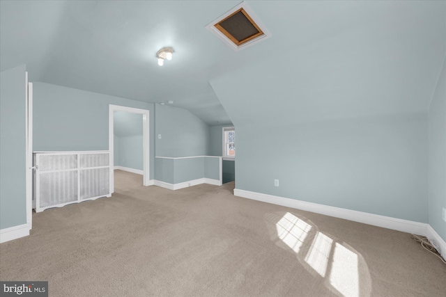 additional living space featuring visible vents, baseboards, lofted ceiling, and attic access