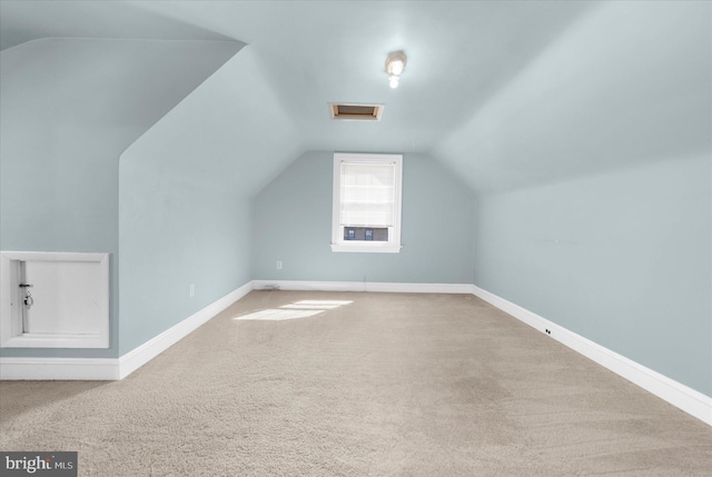 additional living space featuring carpet flooring, attic access, baseboards, and vaulted ceiling