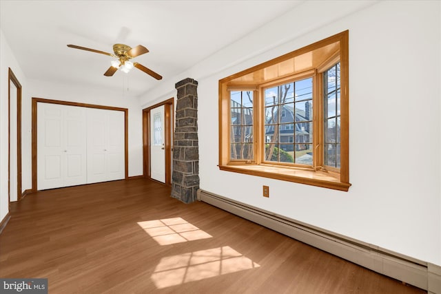 interior space featuring a ceiling fan, wood finished floors, baseboards, a closet, and a baseboard heating unit