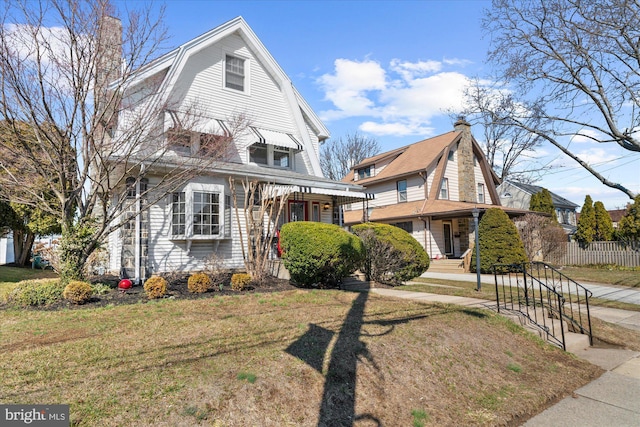 view of front of house featuring a gambrel roof, a front yard, and fence