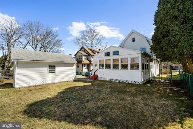 rear view of property featuring a lawn, a shingled roof, a sunroom, and fence