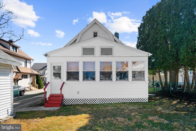 back of property featuring a gambrel roof, entry steps, fence, a yard, and a chimney