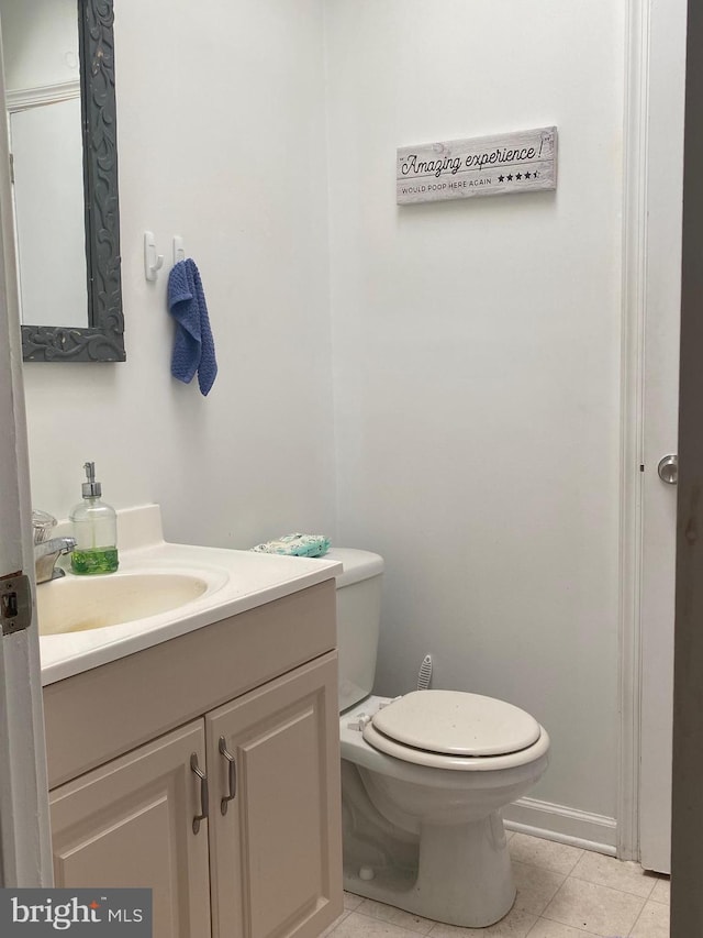 half bath with tile patterned flooring, toilet, and vanity