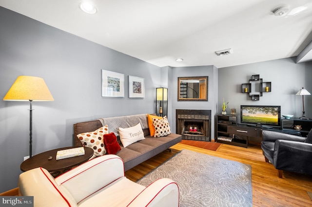 living room with visible vents, recessed lighting, a fireplace with flush hearth, and wood finished floors