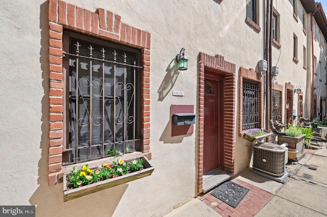 view of exterior entry with stucco siding and cooling unit