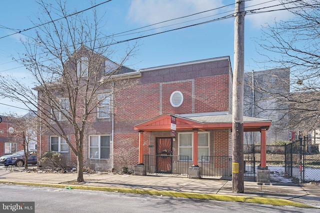 multi unit property featuring a gate, brick siding, and fence