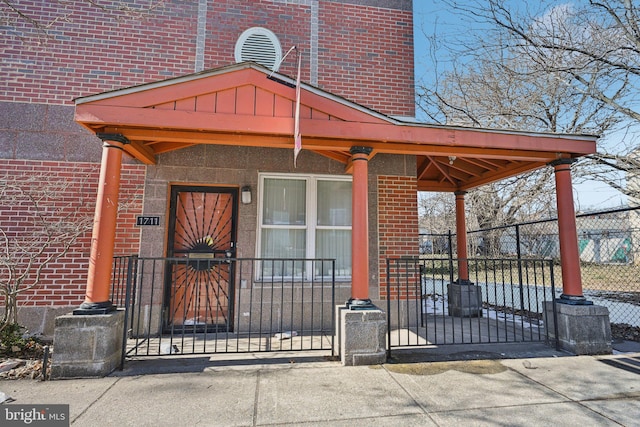 doorway to property featuring board and batten siding, fence, and brick siding