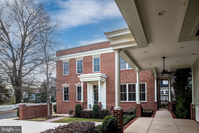 view of front of home with fence, brick siding, and ceiling fan