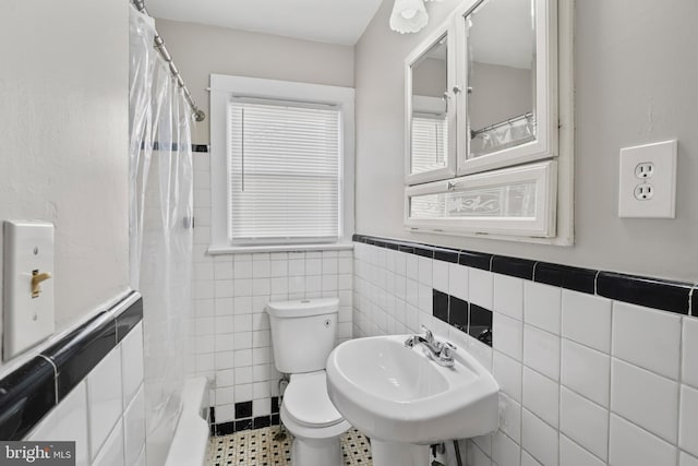 full bathroom with tile walls, toilet, a wainscoted wall, and a sink