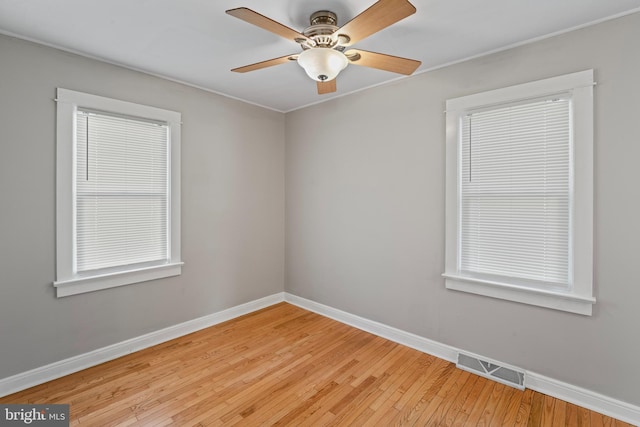 empty room featuring light wood finished floors, visible vents, a ceiling fan, and baseboards