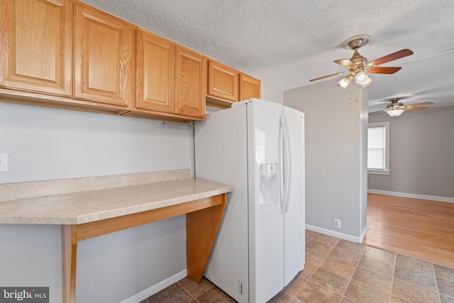 kitchen featuring light countertops, white refrigerator with ice dispenser, baseboards, and a textured ceiling