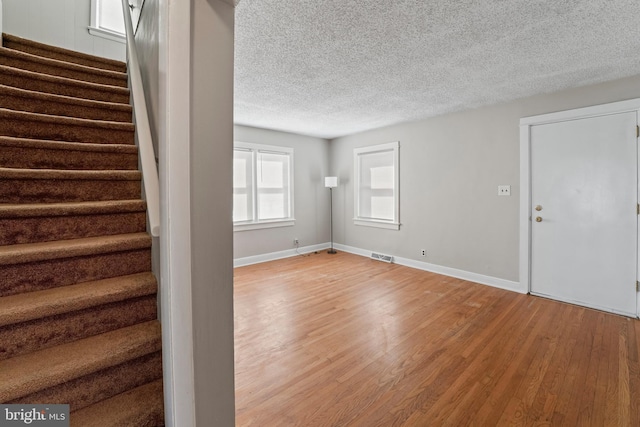 interior space with visible vents, baseboards, stairs, wood finished floors, and a textured ceiling