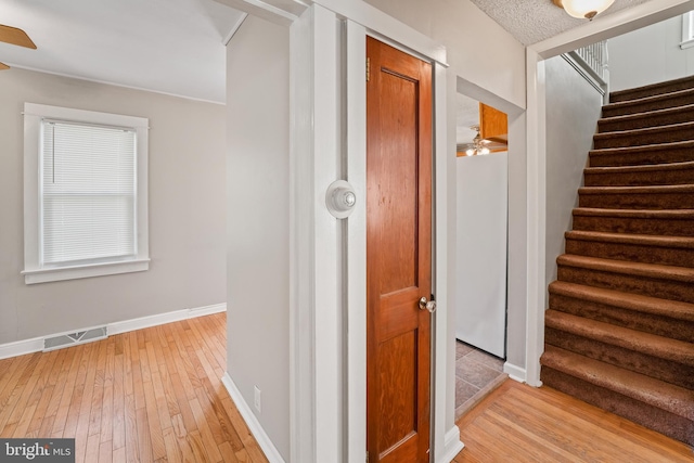 corridor featuring visible vents, baseboards, stairs, and light wood finished floors