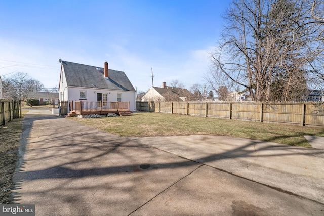 back of property with a deck, a lawn, and a fenced backyard