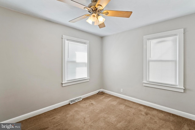 carpeted empty room with visible vents, baseboards, and ceiling fan