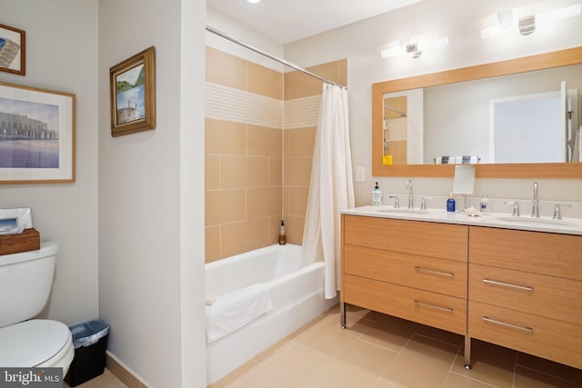 bathroom with tile patterned floors, double vanity, toilet, and a sink