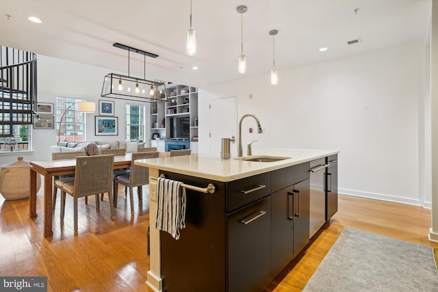 kitchen with visible vents, light wood-type flooring, a sink, light countertops, and hanging light fixtures