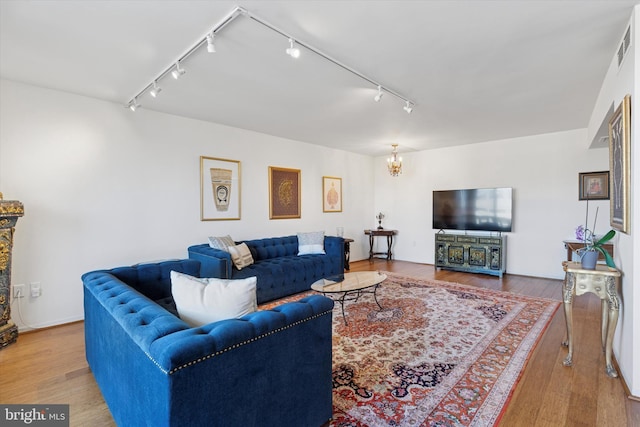 living room with track lighting, a notable chandelier, wood finished floors, and visible vents