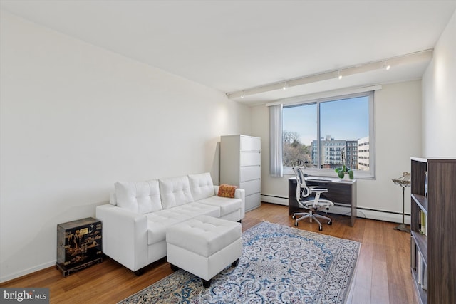 living area featuring hardwood / wood-style floors, track lighting, baseboards, and a baseboard heating unit