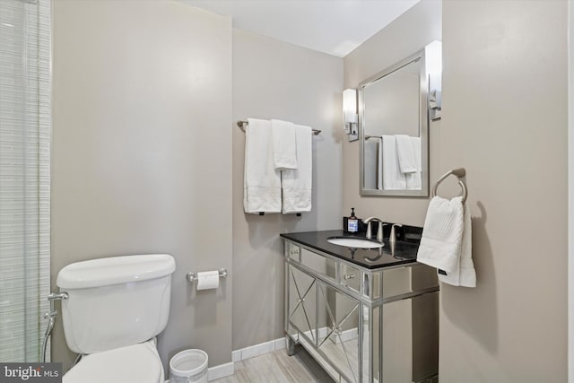 bathroom with baseboards, toilet, wood finished floors, and vanity