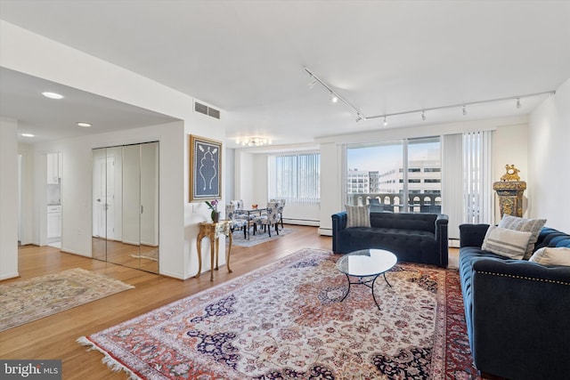 living area featuring wood finished floors, visible vents, and baseboard heating