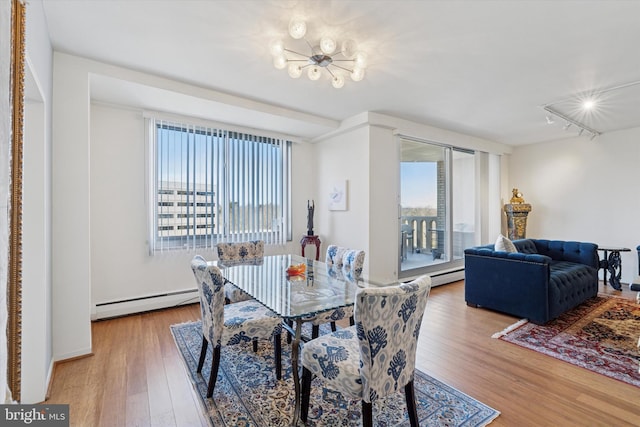 dining room featuring an inviting chandelier, hardwood / wood-style flooring, track lighting, and a baseboard radiator