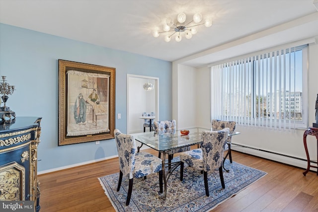 dining room with a baseboard heating unit, wood finished floors, and baseboards