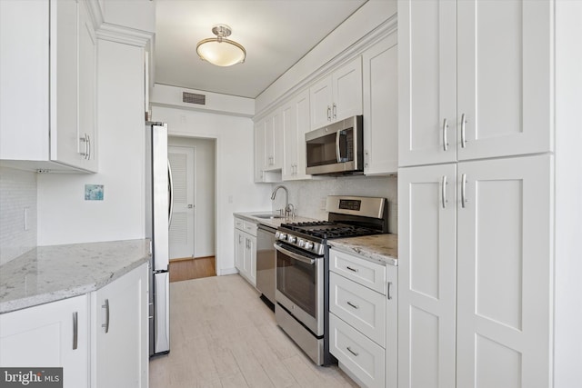 kitchen with tasteful backsplash, visible vents, white cabinets, stainless steel appliances, and a sink