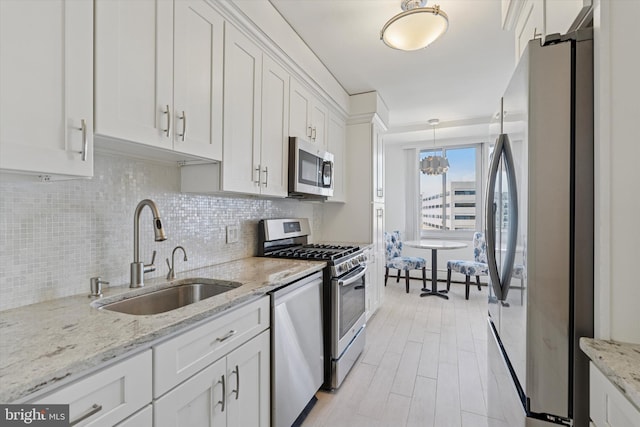 kitchen featuring tasteful backsplash, light wood finished floors, appliances with stainless steel finishes, white cabinets, and a sink