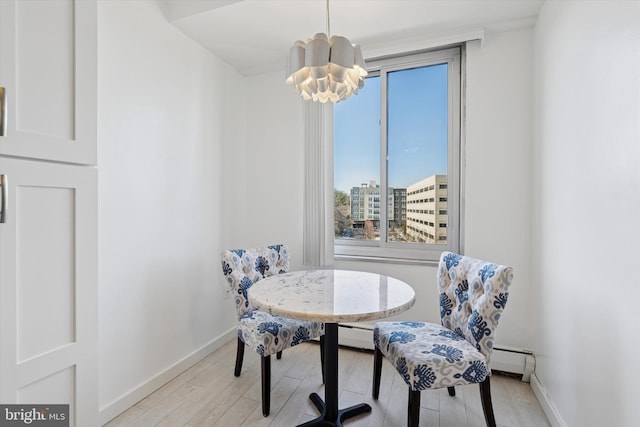 dining room with an inviting chandelier, light wood-style flooring, baseboards, and baseboard heating