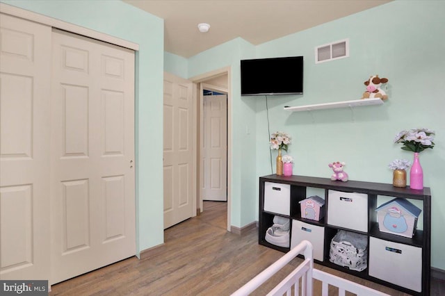 bedroom featuring wood finished floors, visible vents, a closet, and baseboards