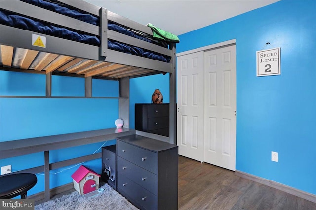 unfurnished bedroom featuring wood finished floors, a closet, and baseboards