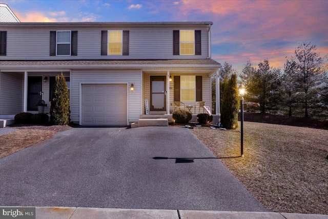 traditional-style house with a porch, an attached garage, and aphalt driveway