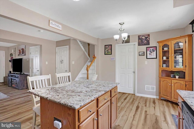 kitchen featuring visible vents, dishwasher, light wood-type flooring, and a kitchen bar