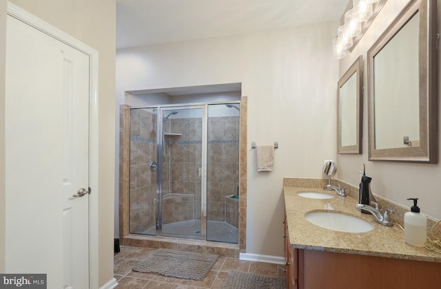 full bathroom featuring a stall shower, tile patterned flooring, a sink, and baseboards