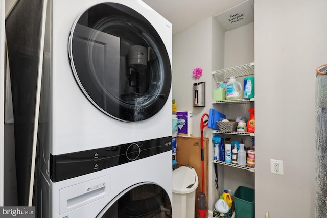 clothes washing area featuring stacked washer and clothes dryer and laundry area